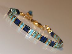 a bracelet with blue stones and gold accents on a white surface, close up view