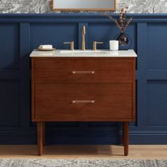 a bathroom vanity with two drawers and a mirror on the wall above it, in front of a blue paneled wall