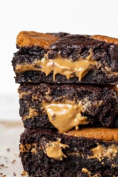 three brownies stacked on top of each other with peanut butter drizzled on them