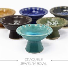 several different colored bowls sitting next to each other on top of a white surface with the words crayole jewelry bowl written below them