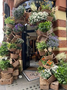 a bunch of baskets that are on the side of a building with flowers in them