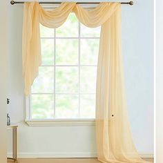 an open window with sheer curtains in the corner and a gold table next to it