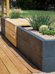 a wooden bench with plants in it sitting on a deck next to grass and trees