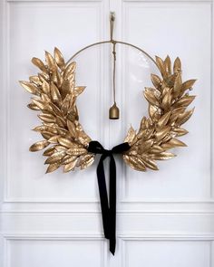 a gold wreath with black ribbon hanging on a white door