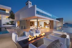 an outdoor living area with white furniture and fire pit