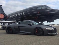 a black sports car parked in front of an airplane