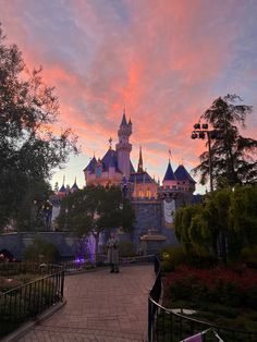 the castle is lit up at sunset with pink clouds