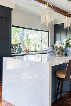 a kitchen with marble counter tops and black cabinets