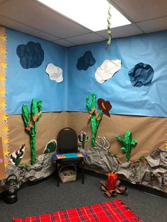 an office cubicle decorated with paper machs, cactus and mountains on the wall