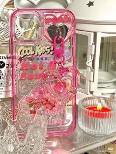 a pink cell phone case sitting on top of a counter next to a glass candle