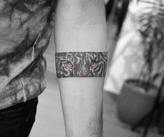 a man's arm with an orange eye and tiger tattoo on the left forearm