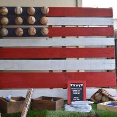 an american flag made out of pallets and other items on the grass with baseballs