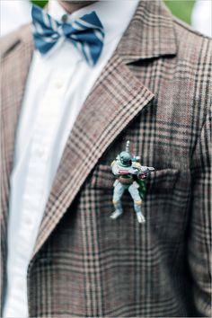 a man wearing a suit and bow tie with a spaceman brooch on his lapel