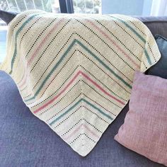 a crocheted blanket sitting on top of a couch next to pillows