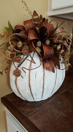 a white pumpkin decorated with flowers on top of a counter