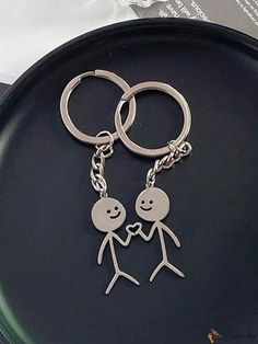 two people holding hands while standing on a black plate with silver key chains attached to it