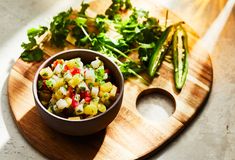 a wooden cutting board topped with a bowl of food