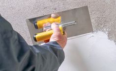 a person using a paint roller to paint a wall with white and yellow paint on it