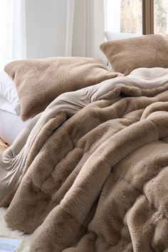 an unmade bed with fluffy blankets and pillows