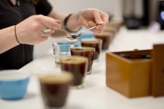 a woman is spooning into some chocolate puddings on a table with other cups