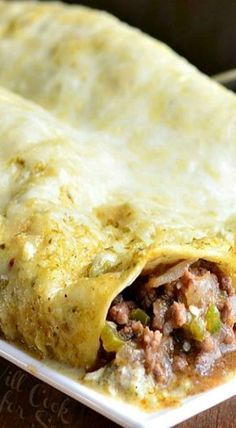 two burritos sitting on top of a white plate covered in meat and cheese