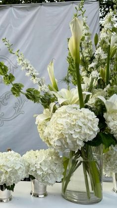 white flowers and greenery in vases on a table