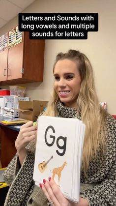 a woman holding up a book with letters and sounds