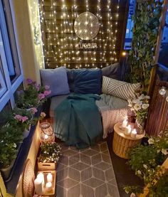 an outdoor patio with candles and potted plants on the floor, surrounded by string lights