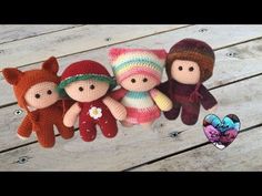 three knitted dolls are sitting next to each other on a wooden surface, one is wearing a hat and the other has a stuffed animal