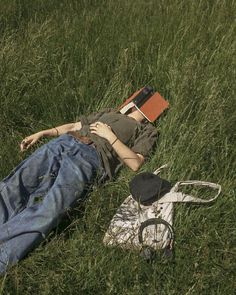 a person laying in the grass with a book and hat on their head next to a pair of scissors