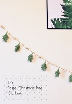 a christmas tree garland with pine cones and green leaves hanging on a wall next to a framed photograph