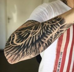 a man is holding his arm with an eagle tattoo on it's left arm