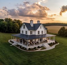 a large white house sitting on top of a lush green field under a cloudy sky