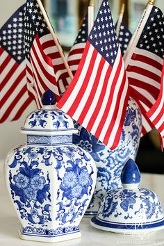 two vases with american flags sticking out of them on top of a white table