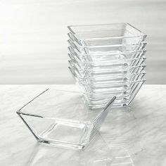 a stack of clear glass containers sitting on top of a white marble countertop next to each other