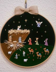 a christmas ornament hanging on a wall with nativity scene in the background