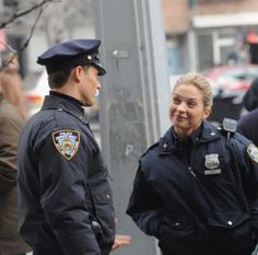 a police officer talking to a woman on the street with other people in the background