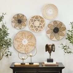 a table topped with lots of baskets on top of it's sideboard next to potted plants