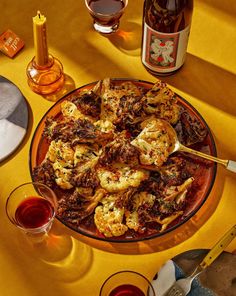 a plate full of food next to some wine and glasses on a yellow table cloth