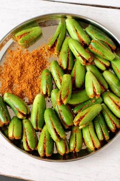 green beans and spices in a metal bowl on a white wooden table with a spoon