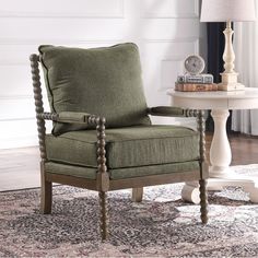 a green chair sitting on top of a rug next to a table with a lamp