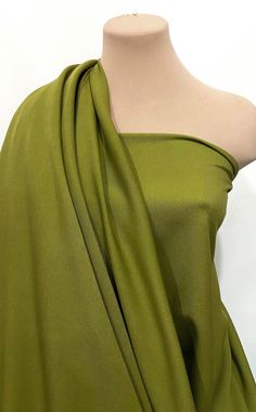 a mannequin wearing a green dress with one shoulder draped over the other,