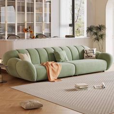 a green couch sitting on top of a hard wood floor next to a white rug