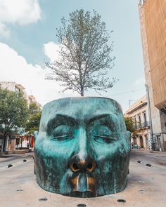 a large green face statue sitting in the middle of a street