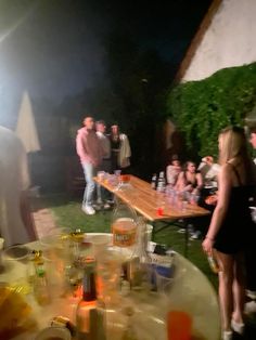 a group of people standing around a table covered in bottles and glasses with drinks on it