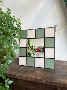 a mirror sitting on top of a wooden table next to a potted green plant