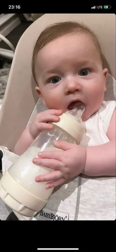 a baby in a high chair drinking from a sippy cup