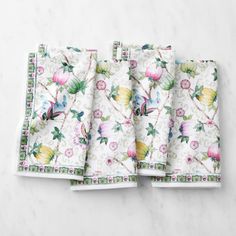 four floral napkins on top of a marble countertop with white and pink flowers