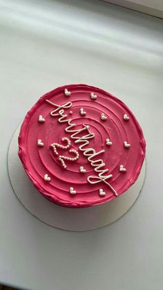 a birthday cake with pink frosting and hearts on it