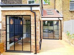 an outdoor living area with sliding glass doors and brick walls, surrounded by wooden decking